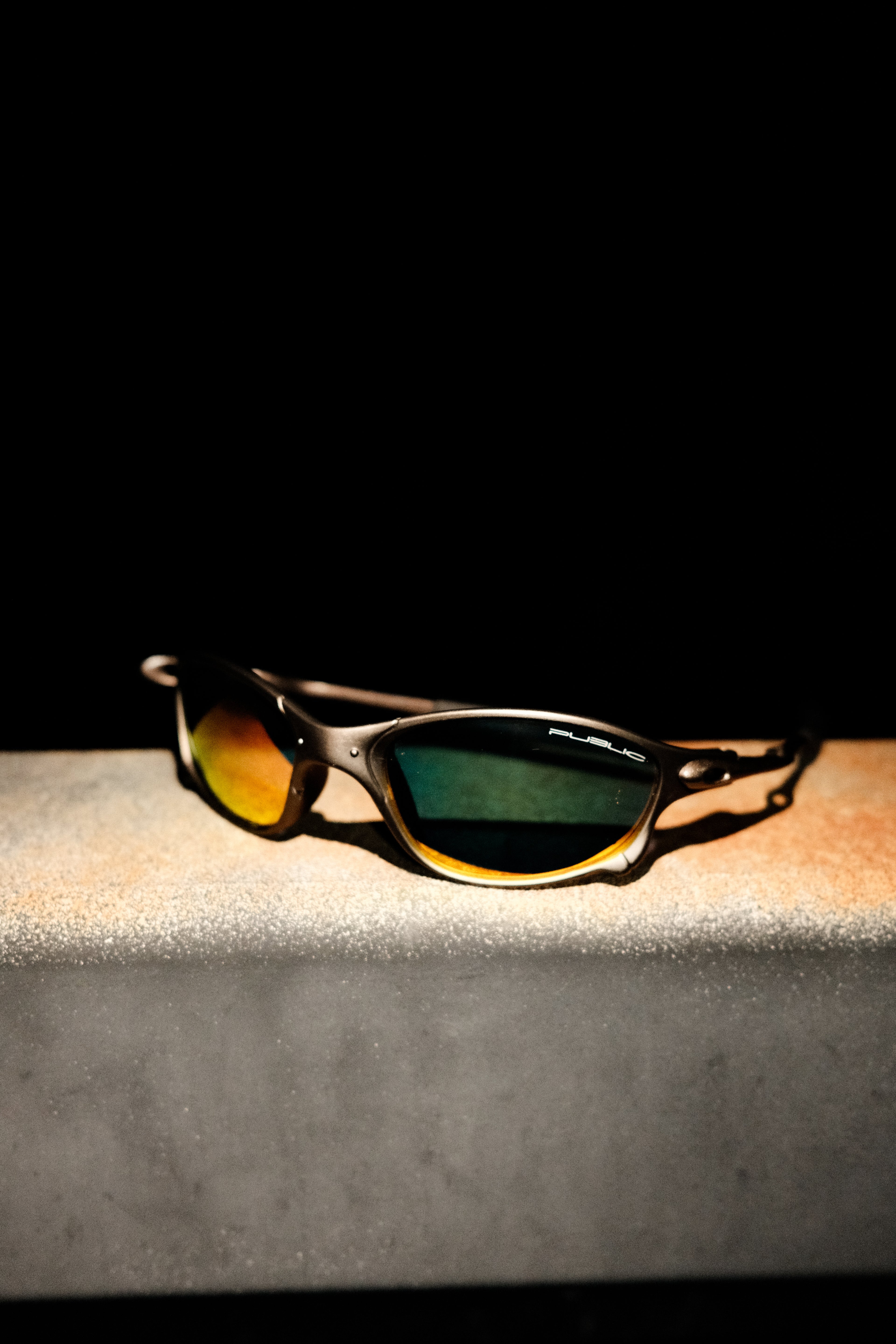 Sunglasses with reflective lenses on a dark surface
